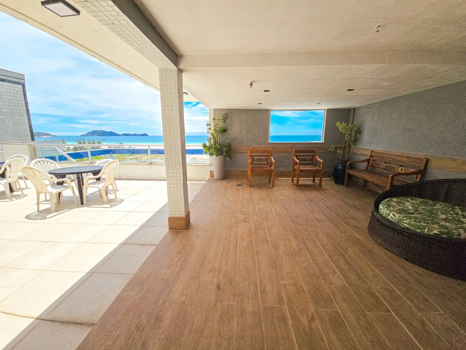 Lounge coberto na cobertura, com bancos de madeira e vista para o mar